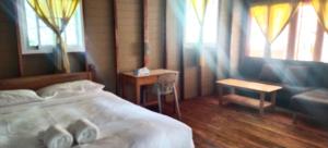 a bedroom with a bed and a couch and windows at Lazy Hut in Ko Phayam