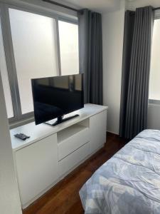 1 dormitorio con TV de pantalla plana en una cómoda blanca en Lujoso departamento en ¨torre Alessandria¨, en Cochabamba