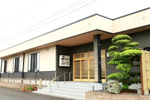 un edificio con un albero di fronte di 民宿ふくだ a Minamiōsaka