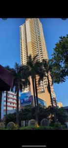 a tall building with palm trees in front of it at Birchtower studio in Manila