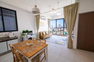 a kitchen and living room with a table and chairs at Urban Suites 2BR Family Setting #19 in Jelutong