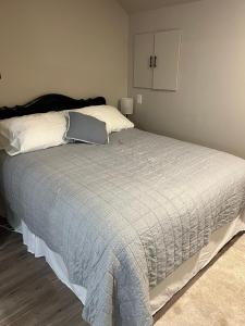 una camera da letto con un grande letto con cuscini bianchi di Entire Basement Guest Suite In Cranbrook a Cranbrook