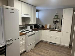 a kitchen with white cabinets and a white refrigerator at Entire Basement Guest Suite In Cranbrook in Cranbrook