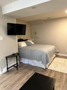 Entire Basement Guest Suite In Cranbrook في كرانبروك: غرفة نوم بسرير وتلفزيون بشاشة مسطحة
