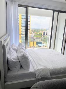 a bed in a room with a large window at Comfy studio near yaya Kilimani in Nairobi