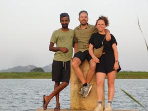 um grupo de três homens e uma mulher sentados numa rocha perto da água em Forest Tree Top Holiday Resort em Buttala