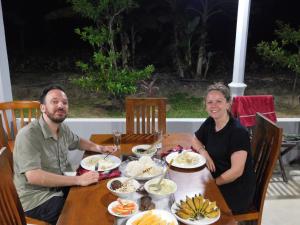 Um homem e uma mulher sentados à mesa com comida. em Forest Tree Top Holiday Resort em Buttala