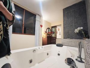 bañera blanca con lavabo y ventana en TURI Suite con Jacuzzi, centro de la ciudad en Baños