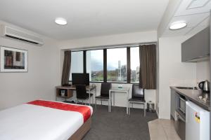 a hotel room with a bed and a desk and a kitchen at Quality Suites Central Square in Palmerston North
