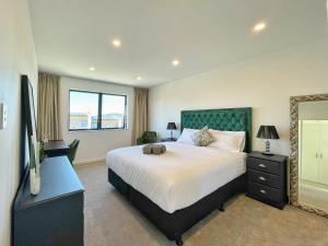 1 dormitorio con 1 cama grande y espejo en Your Modern Home in Sandringham, Close to City, Heat Pumps, Netflix, Parking, en Auckland