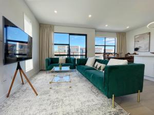 a living room with a green couch and a flat screen tv at Your Modern Home in Sandringham, Close to City, Heat Pumps, Netflix, Parking in Auckland
