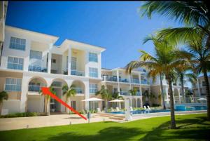 a large white building with a red arrow in front of it at estancia de playa y golf in Punta Cana