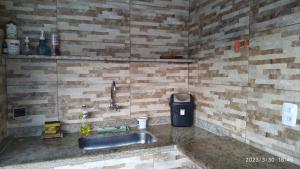 a kitchen with a sink and a brick wall at Tia Rosi tem suite independente 200mts da praia c ar e energia solar c atendimento vip in Rio das Ostras