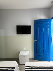 Cette chambre dispose d'une porte bleue et d'une télévision. dans l'établissement Casa Grécia Pousada, à Santo Amaro