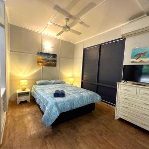 Unit 3 Golden Sands Retreat في Wagait Beach: غرفة نوم بسرير وخزانة وتلفزيون