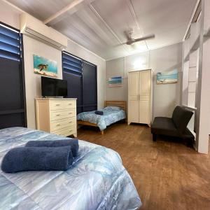 Unit 3 Golden Sands Retreat في Wagait Beach: غرفة نوم بسرير وكرسي وتلفزيون