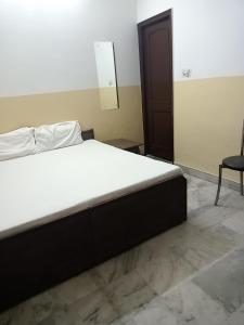 Cette chambre comprend un grand lit et une chaise. dans l'établissement Om Sai palace, à Chandigarh