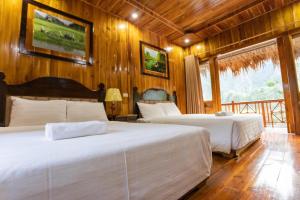 two beds in a room with wooden walls and wooden floors at Hang Lan Bungalow in Ninh Binh