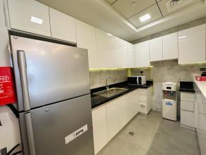 a kitchen with white cabinets and a stainless steel refrigerator at OVAL TOWER in Dubai