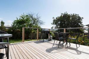 a wooden deck with a table and chairs on it at Homely Cottage: Near the City Wifi & Parking in Newstead