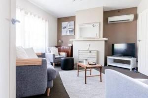 a living room with a couch and a tv at Homely Cottage: Near the City Wifi & Parking in Newstead