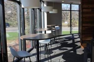 a row of tables and chairs in a room with windows at Onsite coffee bar just mins to Jack Thrice Stadium in Ames