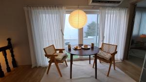 ein Esszimmer mit einem Tisch, Stühlen und einer Lampe in der Unterkunft Soban Stay in Busan