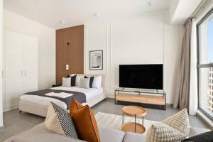 a hotel room with a bed and a television at Silkhaus Studio with Private Beach and Sea View in Abu Dhabi