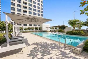 uma piscina com guarda-sol e um edifício em Silkhaus Studio with Private Beach and Sea View em Abu Dhabi
