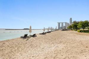 uma praia com cadeiras e guarda-sóis e o oceano em Silkhaus Studio with Private Beach and Sea View em Abu Dhabi
