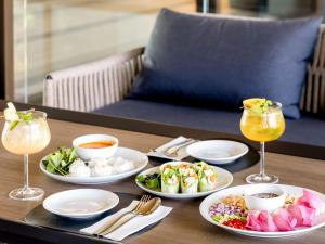 uma mesa com pratos de comida e bebidas em Courtyard by Marriott Bangkok Suvarnabhumi Airport em Banguecoque