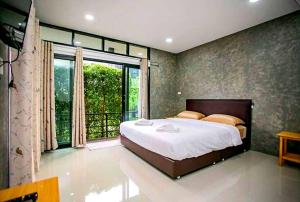 een slaapkamer met een groot bed en een groot raam bij บ้านเราอุทัยธานี โฮมสเตย์ in Uthai Thani