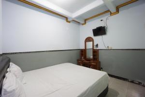 a bedroom with a bed and a mirror and a tv at OYO 93628 Scorpion Guest House & Beach in Tulungagung