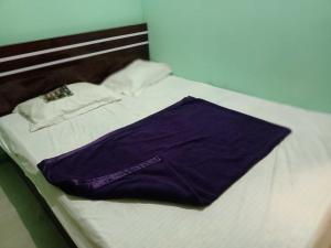 a bed with a purple pillow and a shirt on it at Super OYO Flagship Sofitel Hotel in Dhanbād