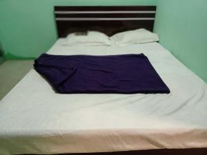 a white bed with a purple blanket on it at Super OYO Flagship Sofitel Hotel in Dhanbād
