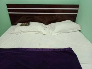 a white bed with two pillows and a wooden headboard at Super OYO Flagship Sofitel Hotel in Dhanbād