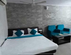 a bedroom with a bed and blue chairs in it at OYO BLUE BARREL HOTEL in Jodhpur