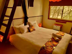 a bedroom with a large white bed with a ladder at Lodge Blue Mount Hakuba in Hakuba