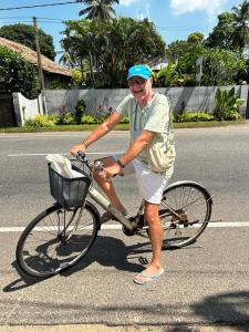 un hombre mayor montando una bicicleta en la calle en Plantation House, en Hikkaduwa