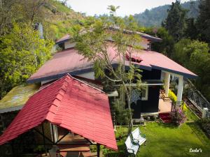 a house with a red roof and two chairs at LEELA's COUNTRY HOUSE in Kodaikānāl
