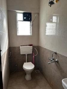 a bathroom with a toilet and a window and a sink at Blissful Stays in Pune
