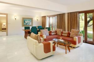 Grand Tropic Suites Hotel Surabaya في سورابايا: غرفة معيشة مع كنب وطاولة