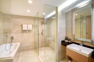 y baño con ducha, bañera y lavamanos. en Grand Tropic Suites Hotel Surabaya, en Surabaya