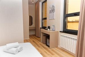 a room with a bed and a window and a desk at Aston Hotel in Aktau