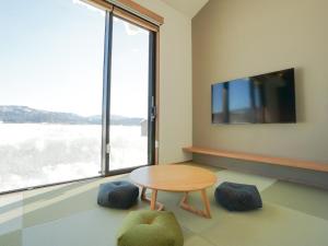 Habitación con mesa y ventana grande. en Hakuba Ryujin Onsen, en Hakuba