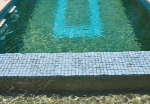 una piscina de agua azul clara con suelo de baldosas en El Pueblo Mérida, en Mérida