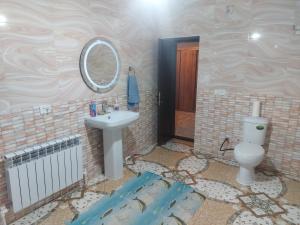 y baño con lavabo, aseo y espejo. en munazhat, en Türkistan