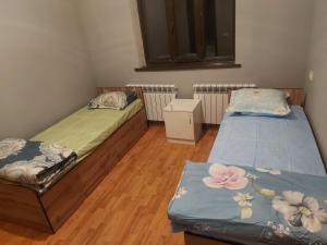 two beds in a room with wooden floors at munazhat in Türkistan