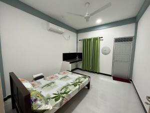 a hospital room with a bed and a green curtain at Victory's Gardens in Mannar