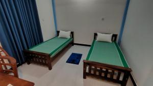 Habitación con 2 camas y silla en Victory's Gardens, en Mannar